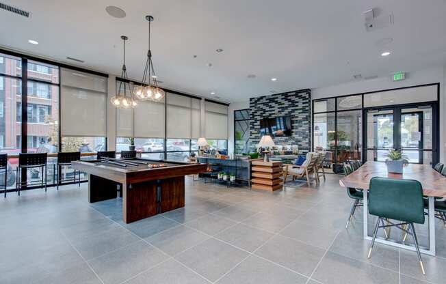 a communal area with a pool table and a dining area with chairs and tables