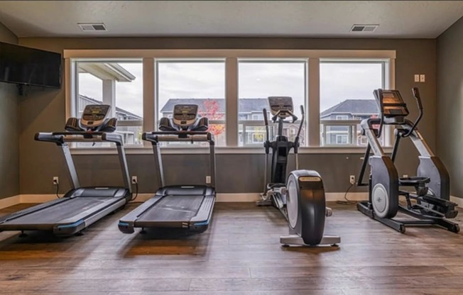 a gym with cardio equipment and windows with a mountain view