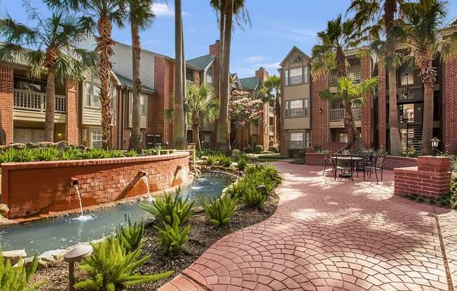 a courtyard with a fountain and tables and buildings with palm trees