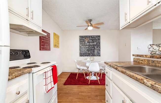 a kitchen with white cabinets and appliances and a dining room with a table and chairs