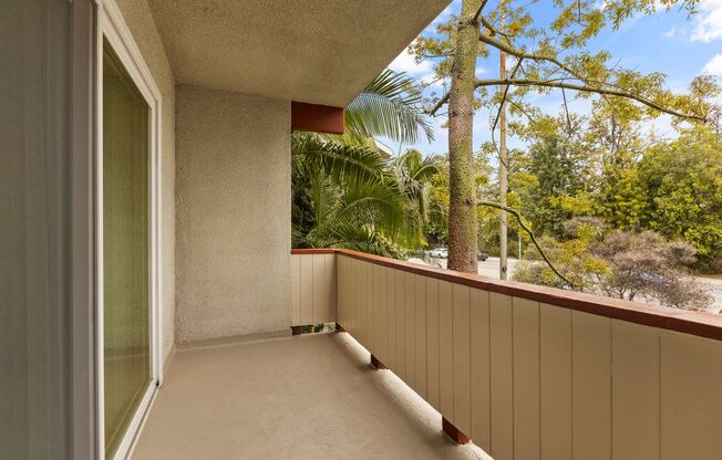 A balcony with a view of trees and a clear sky.