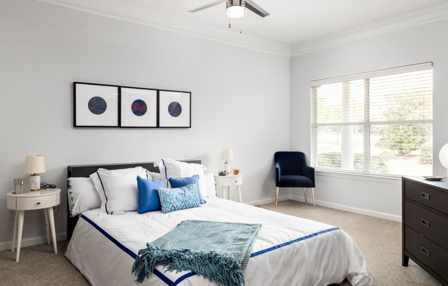 a bedroom with white walls and a white bed with blue and white bedding