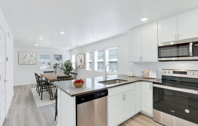 a kitchen with white cabinets and stainless steel appliances and a dining room table