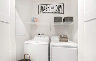A laundry area with a washer and dryer and a shelf above them at Andover Pointe Apartment Homes, La Vista, NE, 68138