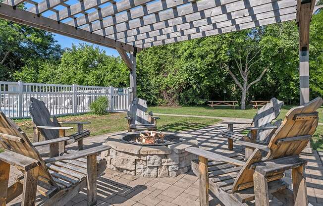 a patio with wooden chairs and a fire pit