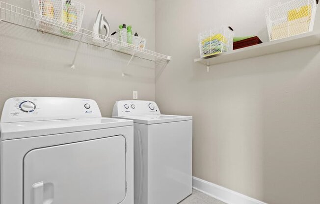 a white laundry room with two washes and a dryer