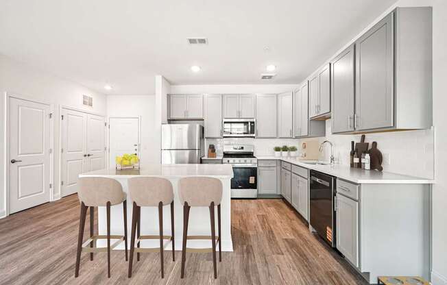 A modern kitchen with a white countertop and wooden flooring.