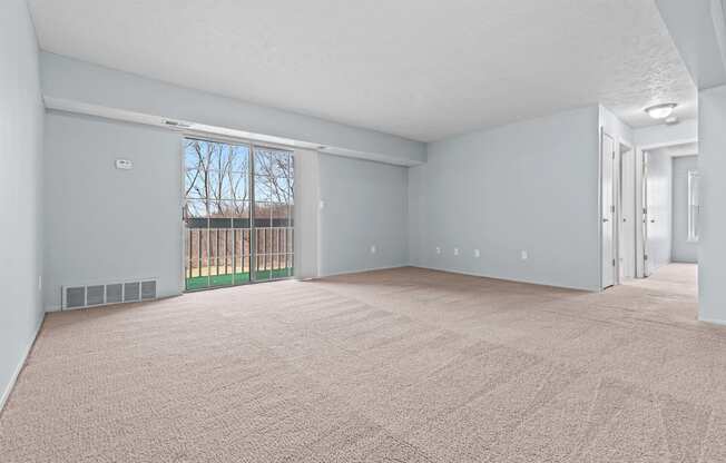 an empty living room with a sliding glass door to a balcony