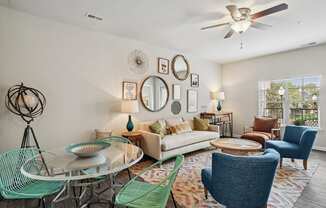 a living room with a ceiling fan and a round glass table