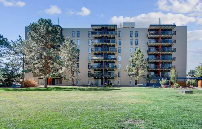 A large apartment building with balconies and a green lawn in front.