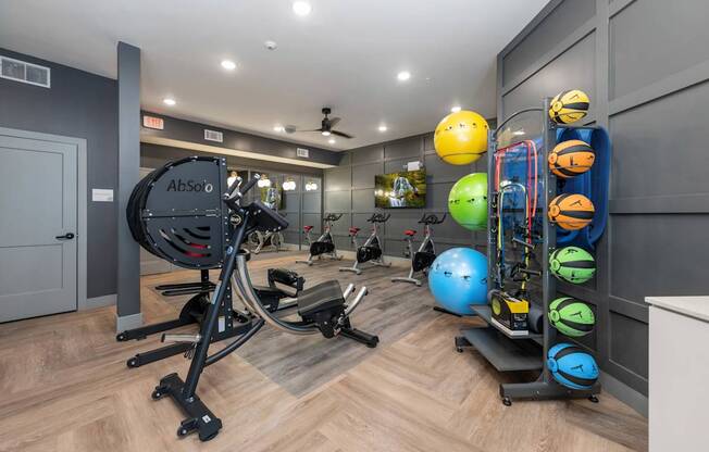 A gym with a variety of equipment including a weight bench, a rowing machine, and a rack of exercise balls.