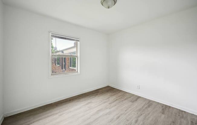 A room with a window and wooden flooring.