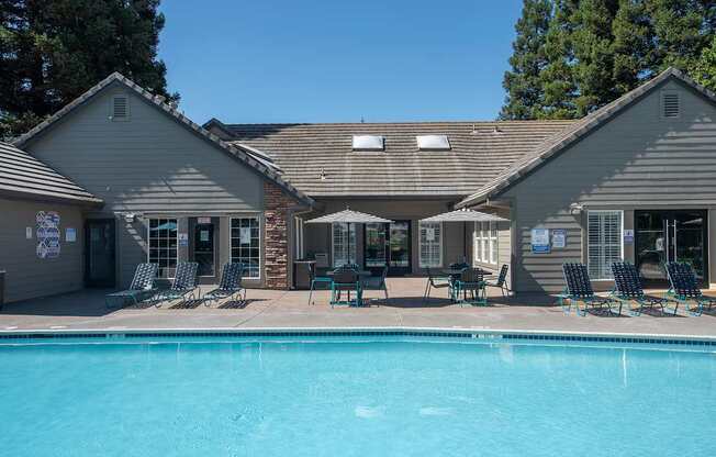 A swimming pool is surrounded by chairs and umbrellas outside at Sunset Summit, Rocklin, CA, 95765