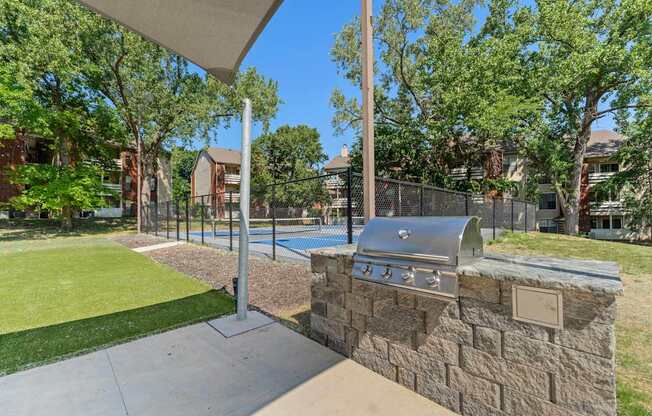 A BBQ grill is attached to a stone wall.