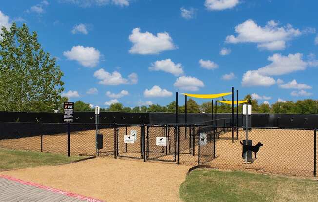 A dog park with a yellow canopy and a black fence.
