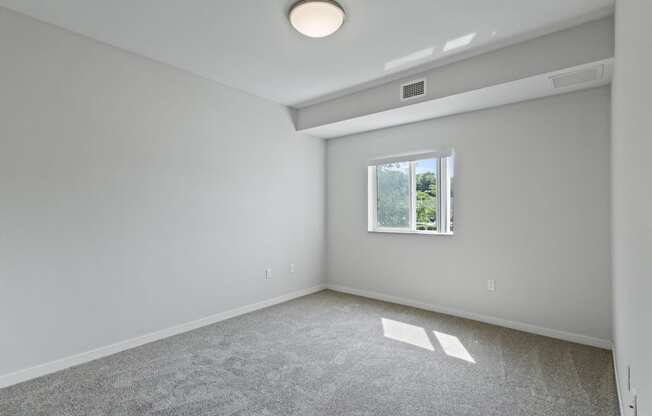 an empty room with white walls and a window