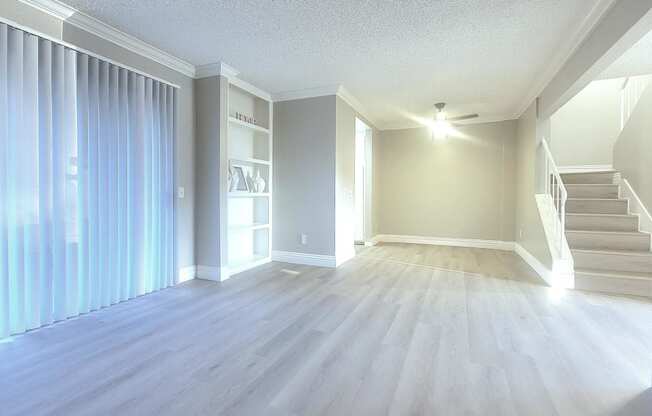 an empty living room with a staircase and a window