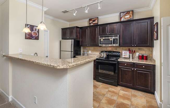 A kitchen with brown cabinets and a granite counter.
