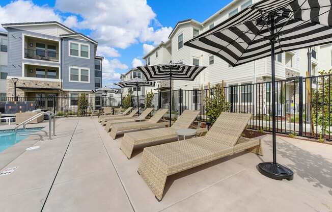Pool-side lounge chairs with black and white umbrellas for shade at Morgan Ranch Apartments, Morgan Hill, 95037
