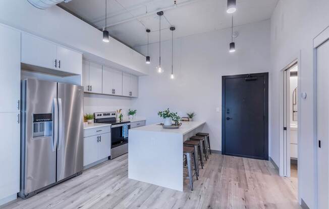 A modern kitchen with a refrigerator, stove, and bar stools.