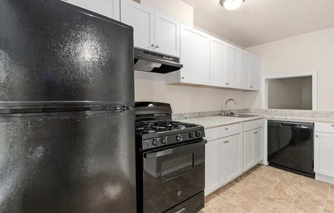 a kitchen with white cabinets and black appliances