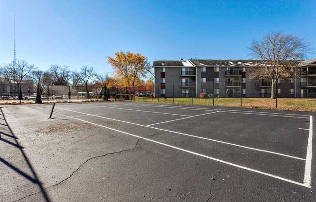 an empty parking lot with an apartment building in the background at Sutton Hill Apartments, IOWA