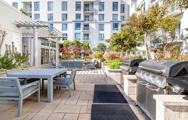a patio with a table and chairs and a barbecue grill