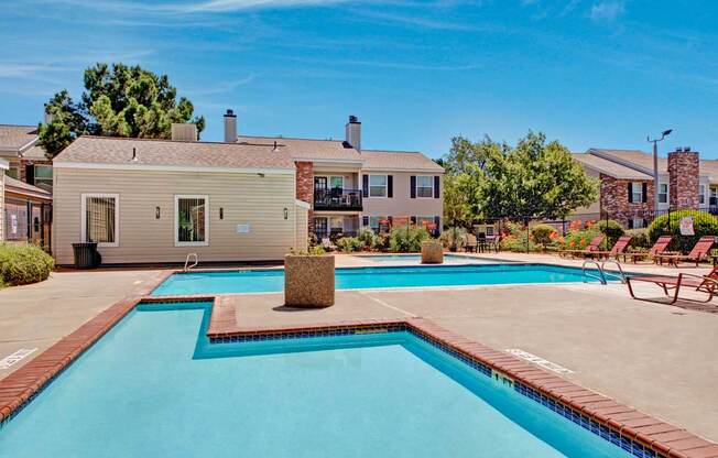 A refreshing outdoor swimming pool here at Cypress Pointe with clear blue water, wide pool decking, and surrounding lounge chairs for relaxing in the sun. A landscaped setting with nearby apartment buildings creates a welcoming, community-focused outdoor space.