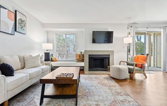 A living room with a white couch, a coffee table, a fireplace, and a television.