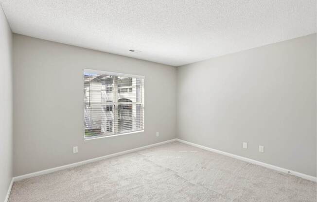 A room with a window and carpeted floor.