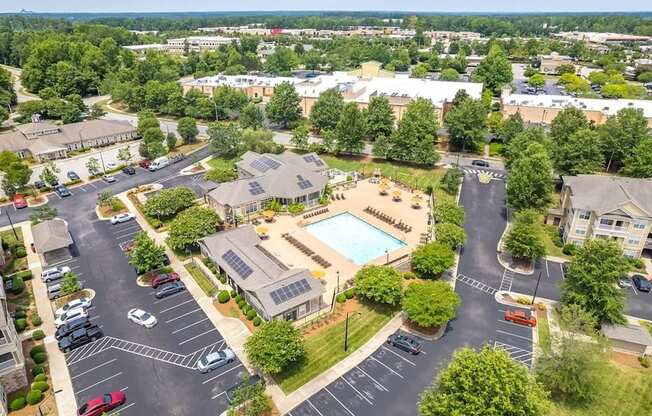 A bird's eye view of a parking lot with a swimming pool and buildings in the background.
