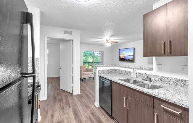 A kitchen with a black fridge and wooden cabinets.