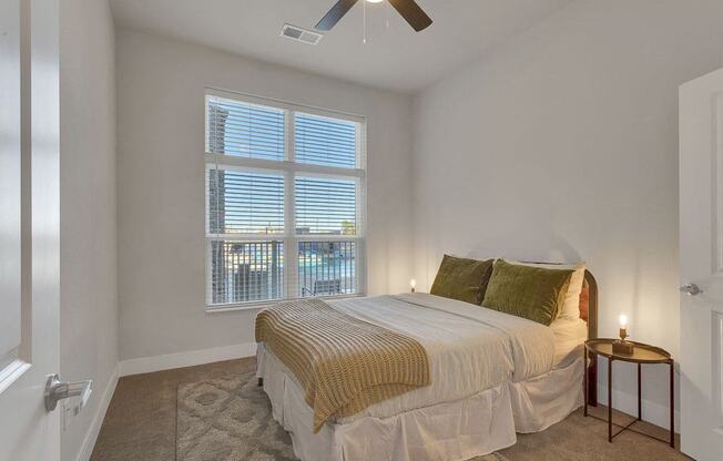 A bedroom with a bed, pillows, and a ceiling fan.