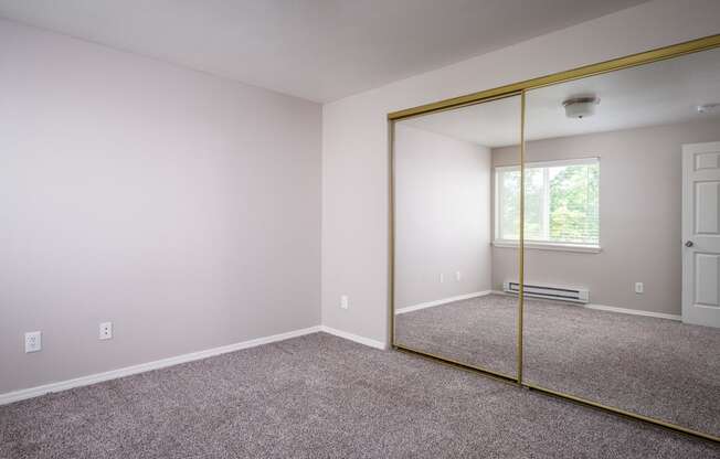 a bedroom with carpet and a large mirror