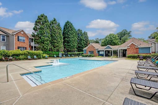 A swimming pool surrounded by lounge chairs and trees.