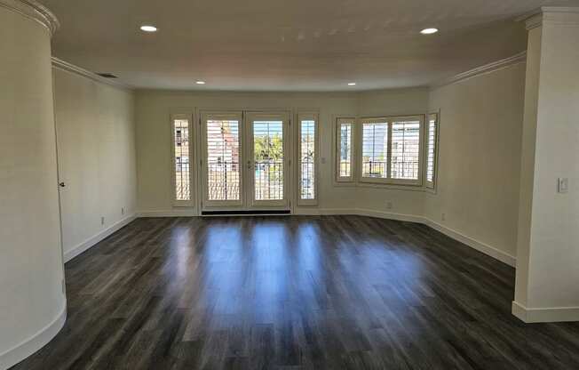 an empty living room with wooden floors and windows