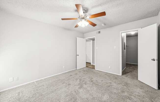 A room with a ceiling fan and carpeted floor.