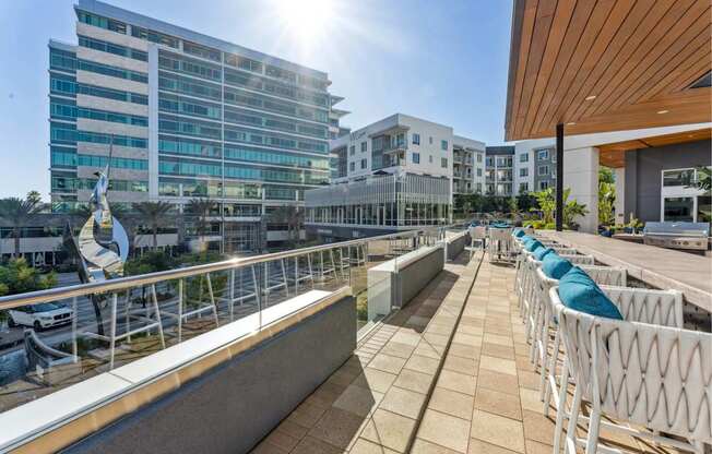A sunny day at a modern building with a balcony and chairs.