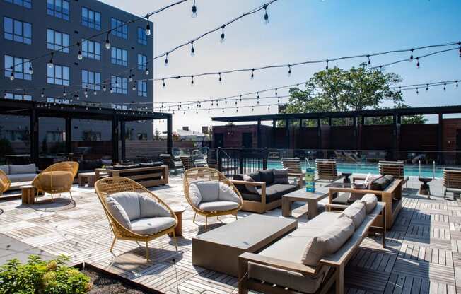 a rooftop lounge area with chairs and tables and a pool