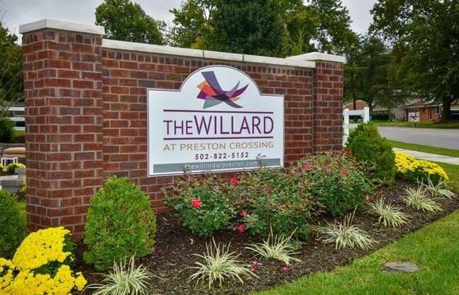 a sign for the willard at prestons crossing in front of a garden