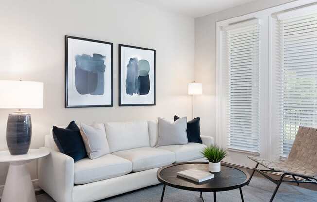 a living room with a white couch and two paintings on the wall