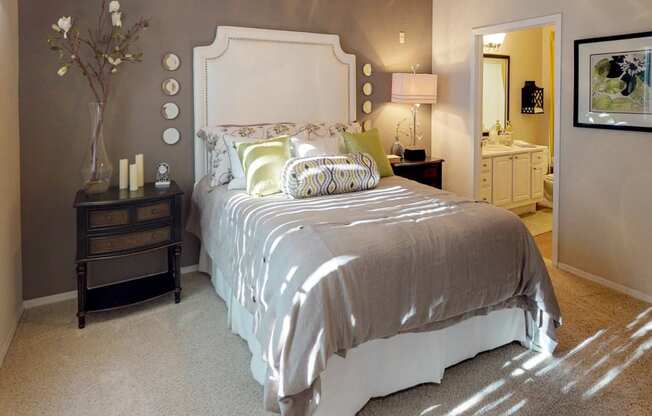 Classically decorated bed with night stand and view of master bathroom