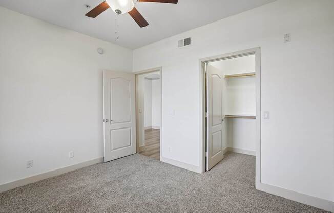 A room with a ceiling fan and two doors.
