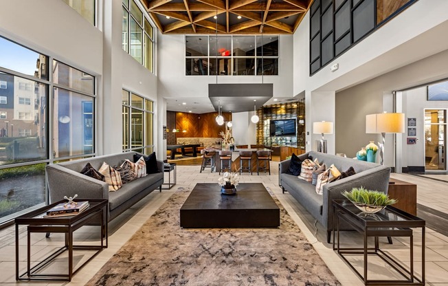 A large, modern living room with a high ceiling and a view of the city.
