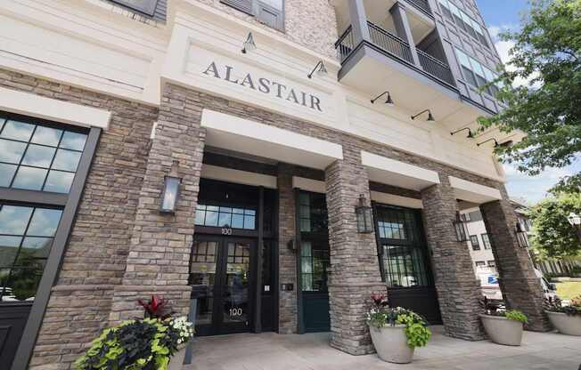 The Alastair at Aria Village leasing office entrance with stone brick pillars and potted flowers in Sandy Springs, GA