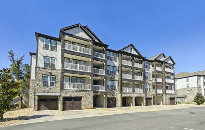 View from an angle of an apartment building with built-in garage parking spaces and private balconies at Evergreen at Southwood in Tallahassee, FL