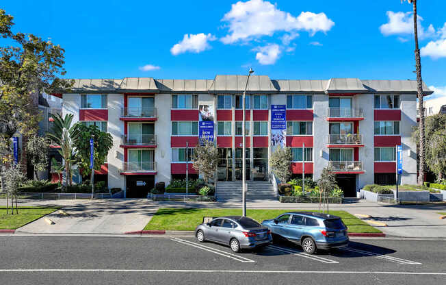 A multi-story building with a red and white facade has a blue banner on the front.