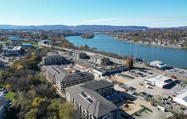 A large building complex sits in front of a body of water with a parking lot in front of it.