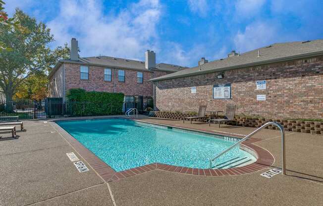 A pool surrounded by a brick wall and a bench.