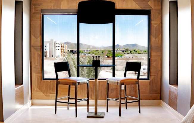 Two bar stools are in front of a large window.